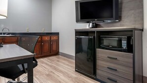 Eine moderne Küche mit Flachbildfernseher, integriertem Mikrowellenherd und Kühlschrank.