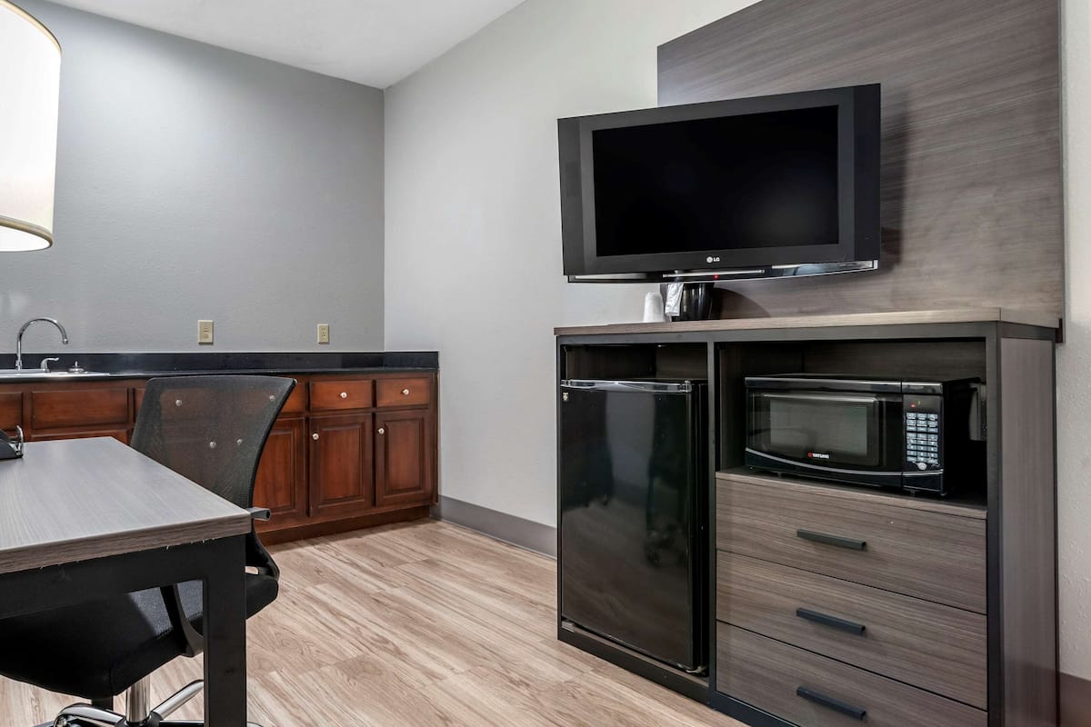 A modern kitchen with a flat-screen TV, a built-in microwave, and a refrigerator.