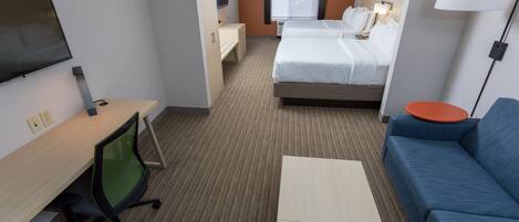 A hotel room with a bed, a desk, a chair, a sofa, and a TV.