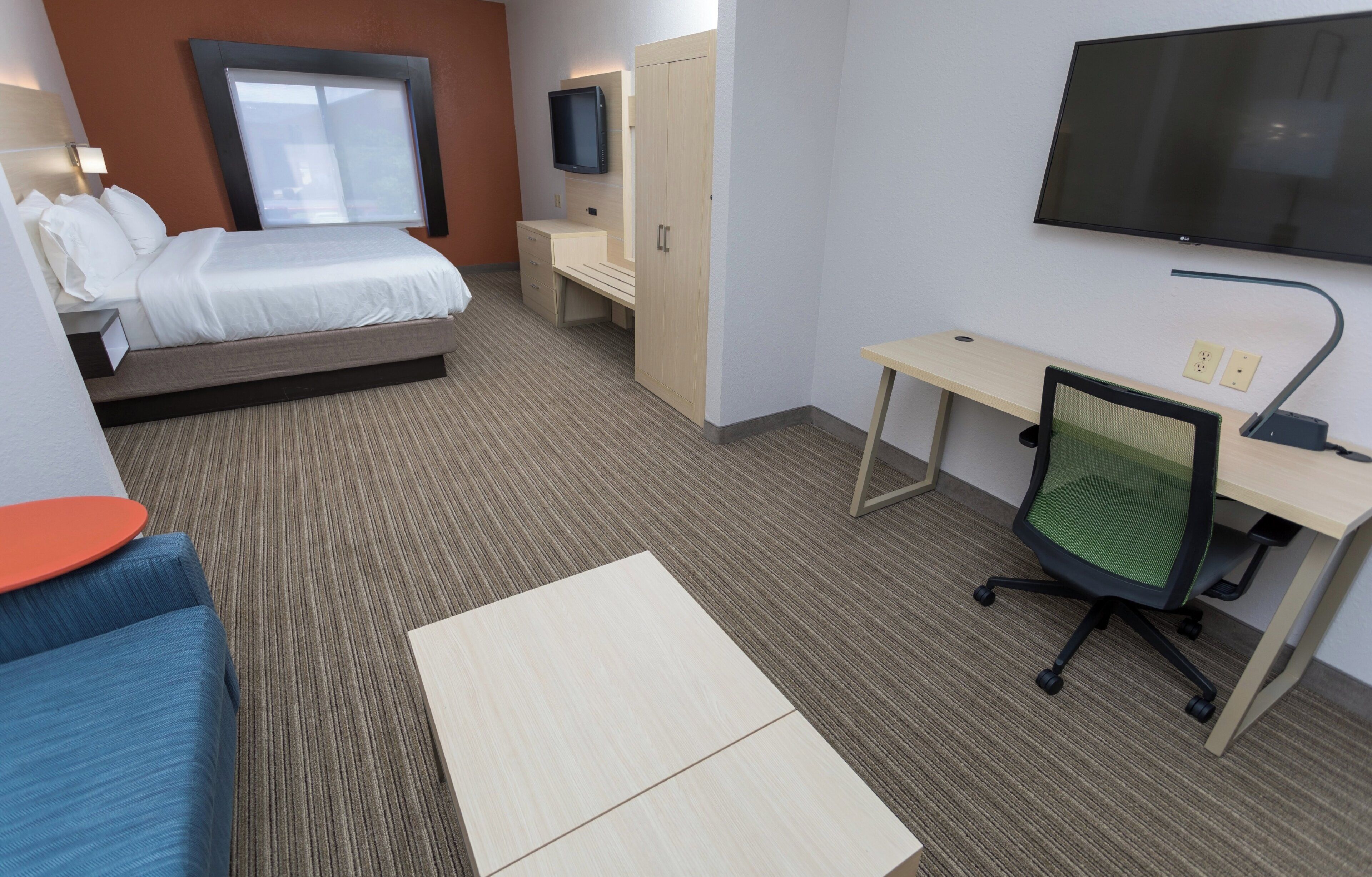 Habitación de hotel con cama, escritorio, silla, televisor y ventana.