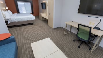 Habitación de hotel con cama, escritorio, silla, televisor y ventana.