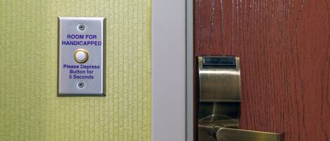 A door with a sign indicating a room for handicapped individuals and a button to depress for 5 seconds.