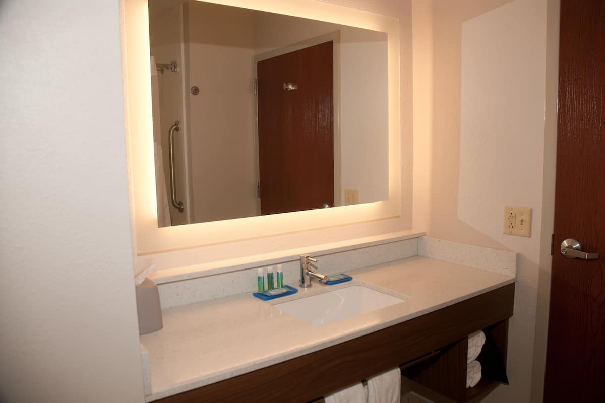 A bathroom with a white sink, a mirror, and a wooden vanity.