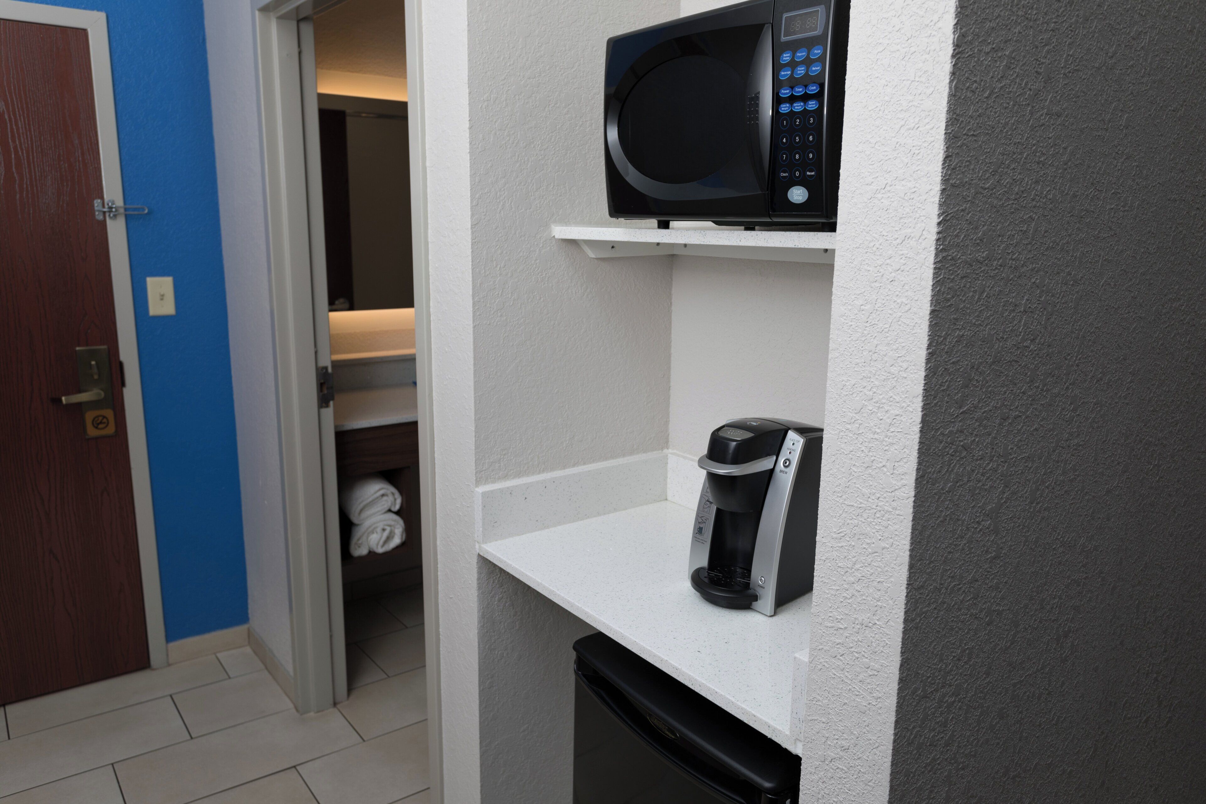 A compact kitchenette with a microwave, coffee maker, and a small dishwasher.