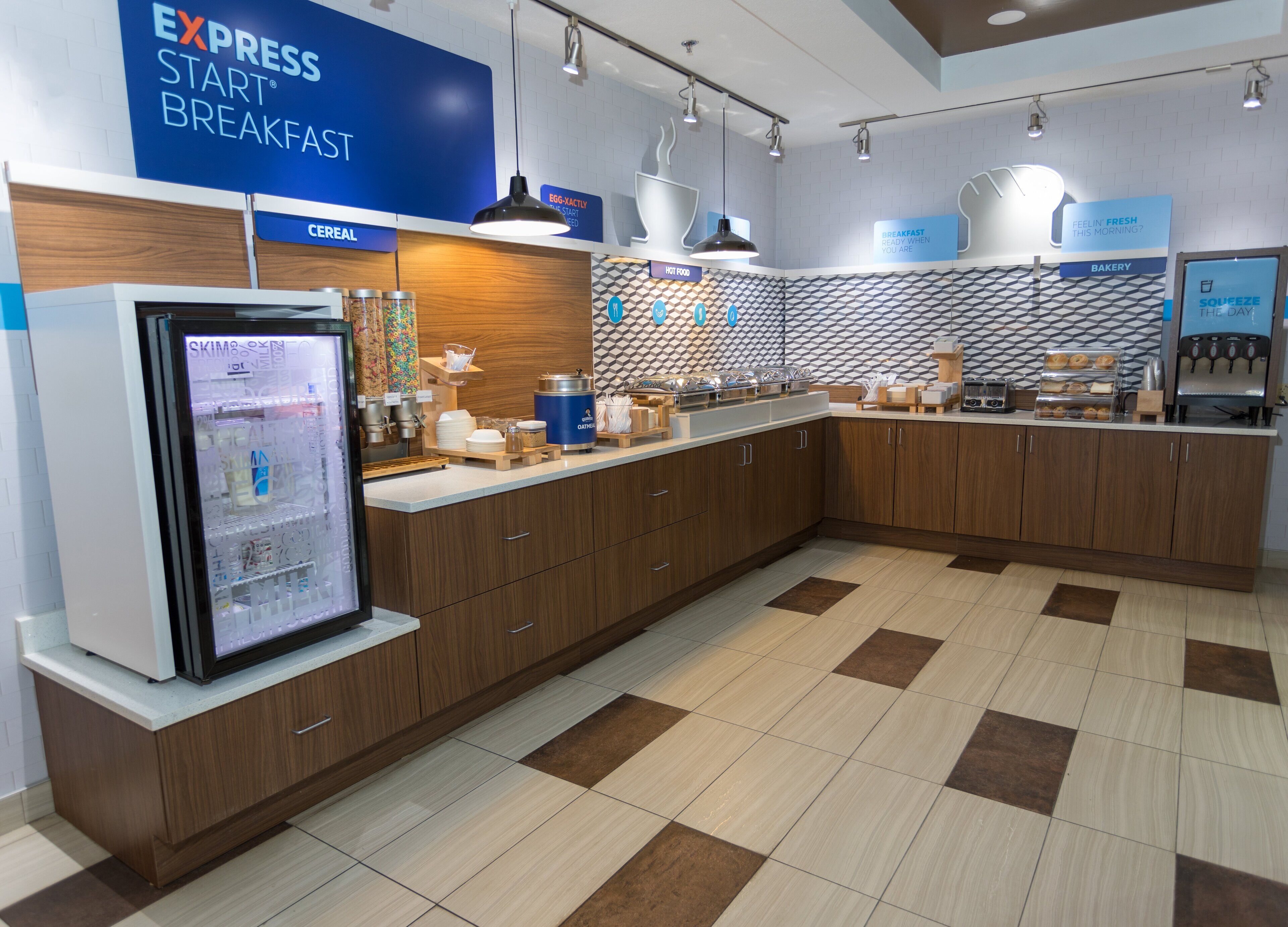 Un área de desayuno moderna con un expositor refrigerado, sección de cereales y panadería.
