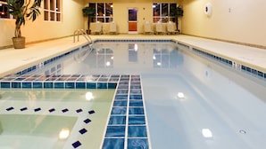 Una piscina con bordi piastrellati, una scaletta e sedie a sdraio.