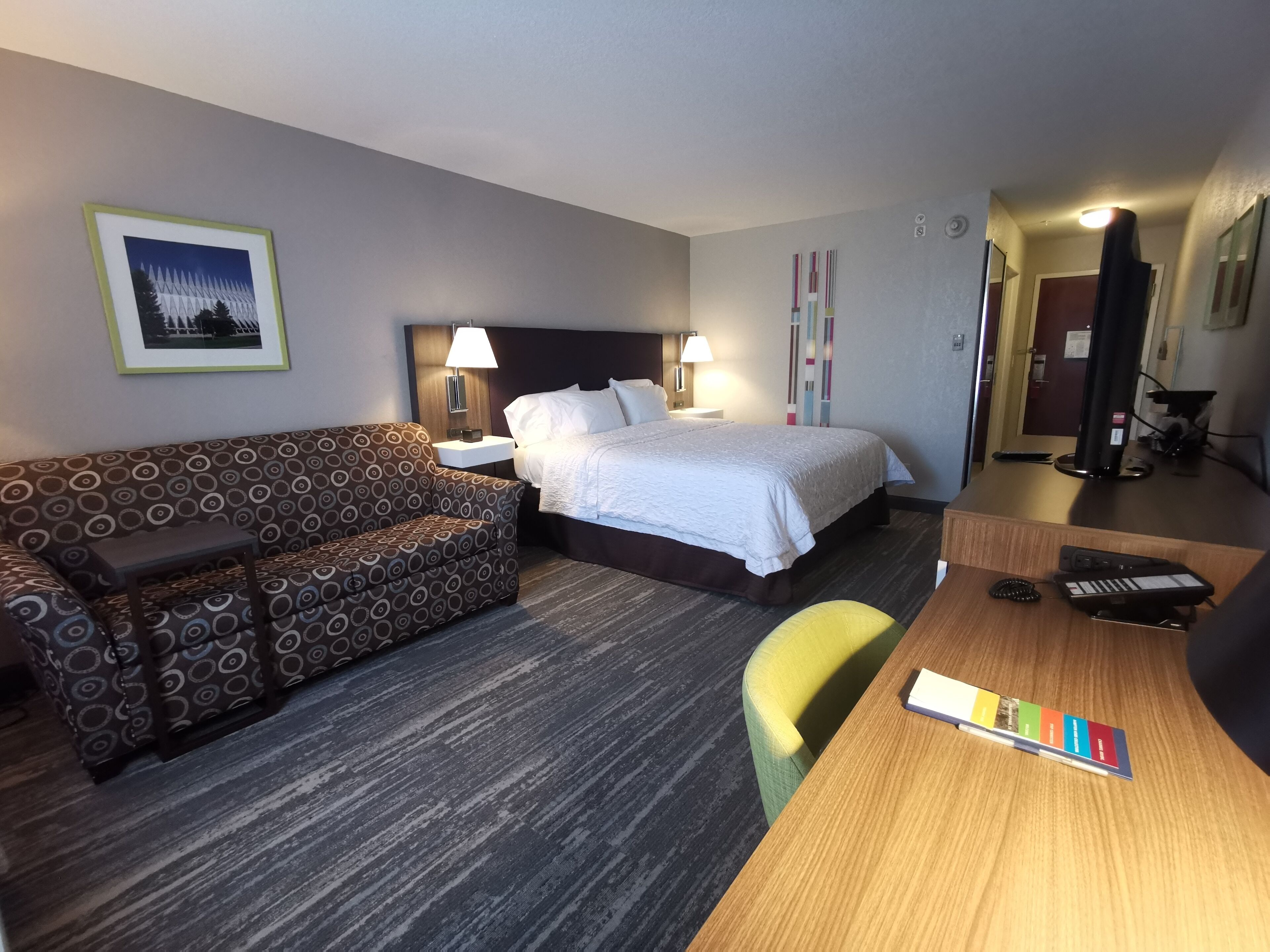 Una habitación de hotel con cama, sofá, escritorio y silla.