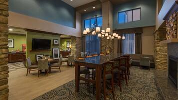 A spacious living room with a large dining table, comfortable seating, a stone fireplace, and a television.