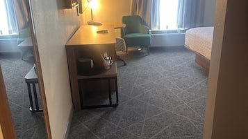 A hotel room with a sofa, a small table, a lamp, and a bed.