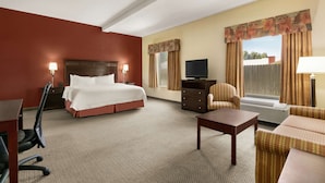 A hotel room with a bed, a desk, a chair, a TV, and a window with curtains. - Hampton Inn & Suites Lawton (Lawton)