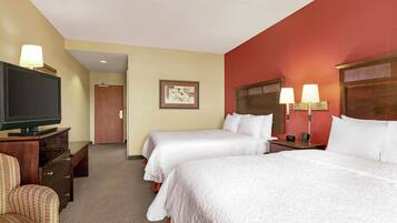 A hotel room with two beds, a TV, a desk, and a chair.