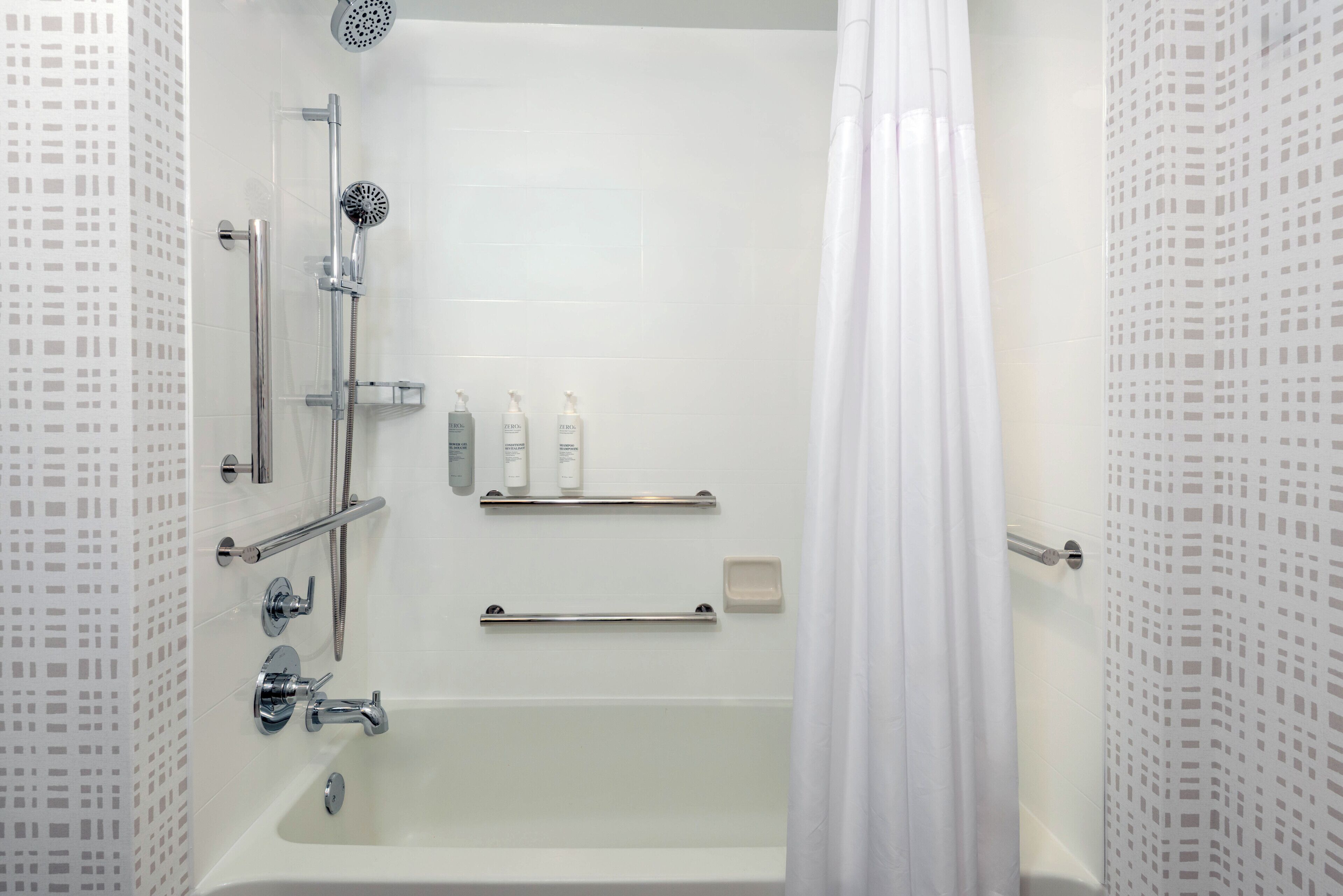 Un baño moderno con bañera, ducha y barras de apoyo.