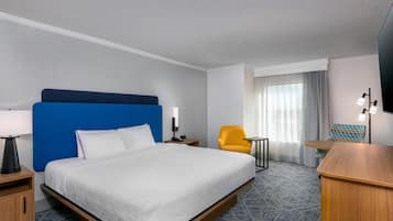 Una habitación de hotel con una cama grande, un escritorio, una silla y una mesita.