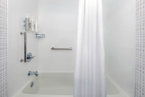 A bathroom with a bathtub, a shower curtain, and toiletries on the wall.