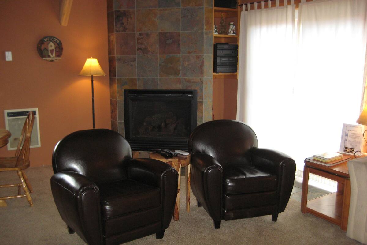 A living room with two leather armchairs, a television, and a small table with a lamp.