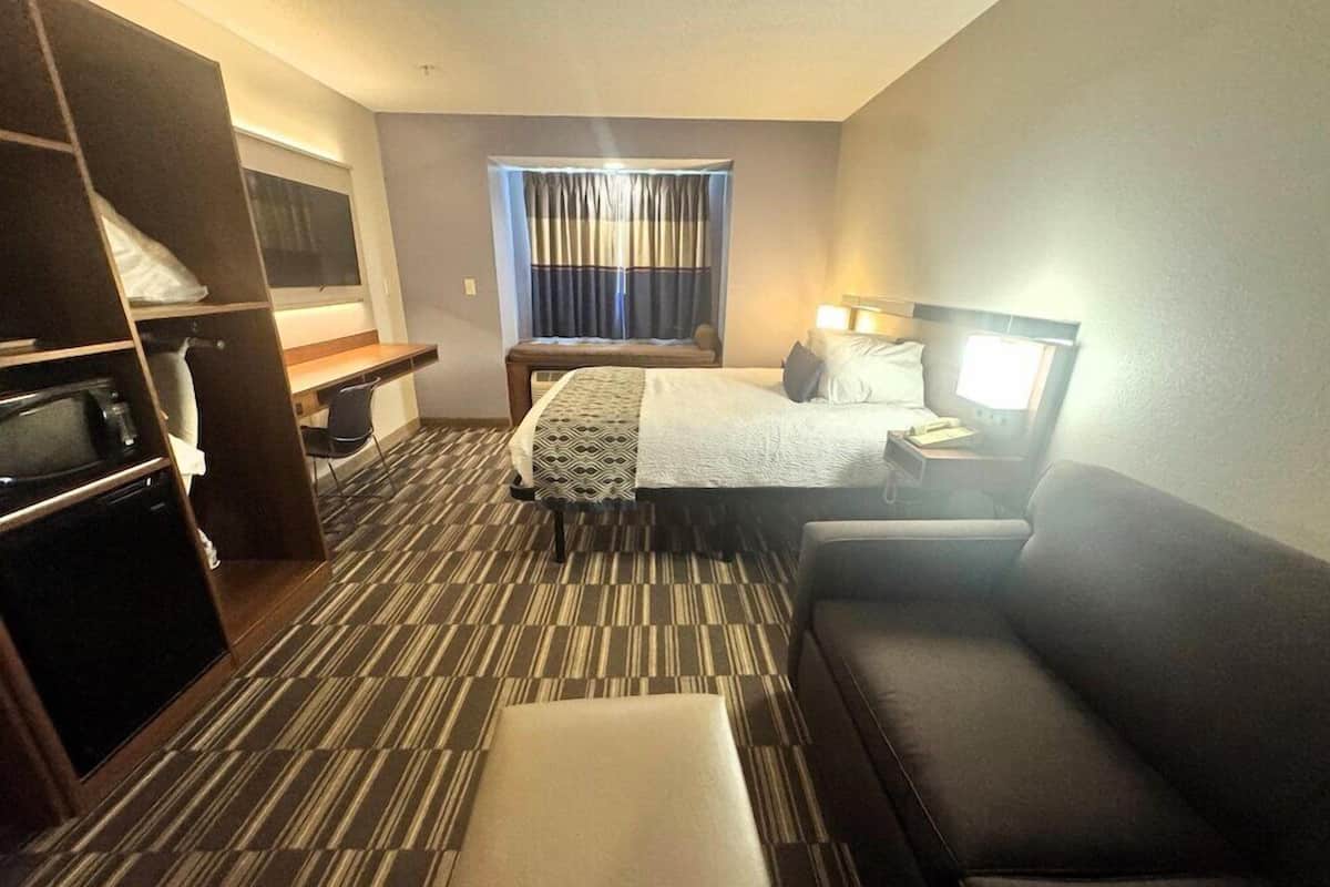 A hotel room with a bed, a sofa, a desk, and a wardrobe.