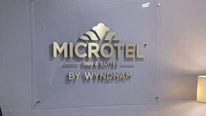 Señal de Microtel Inn & Suites con un sillón tapizado gris al frente.