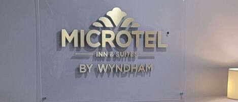 A Microtel Inn & Suites sign with a grey upholstered armchair in front.