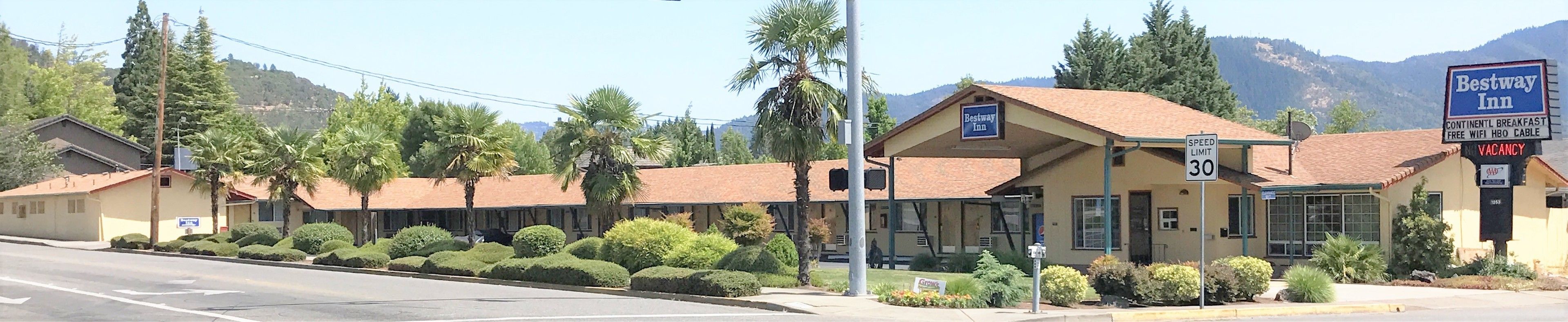 A Bestway Inn with a speed limit sign of 30 mph, surrounded by well-maintained landscaping and a mountainous backdrop.