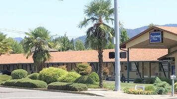 A Bestway Inn with a speed limit sign of 30 mph, surrounded by well-maintained landscaping and a mountainous backdrop.