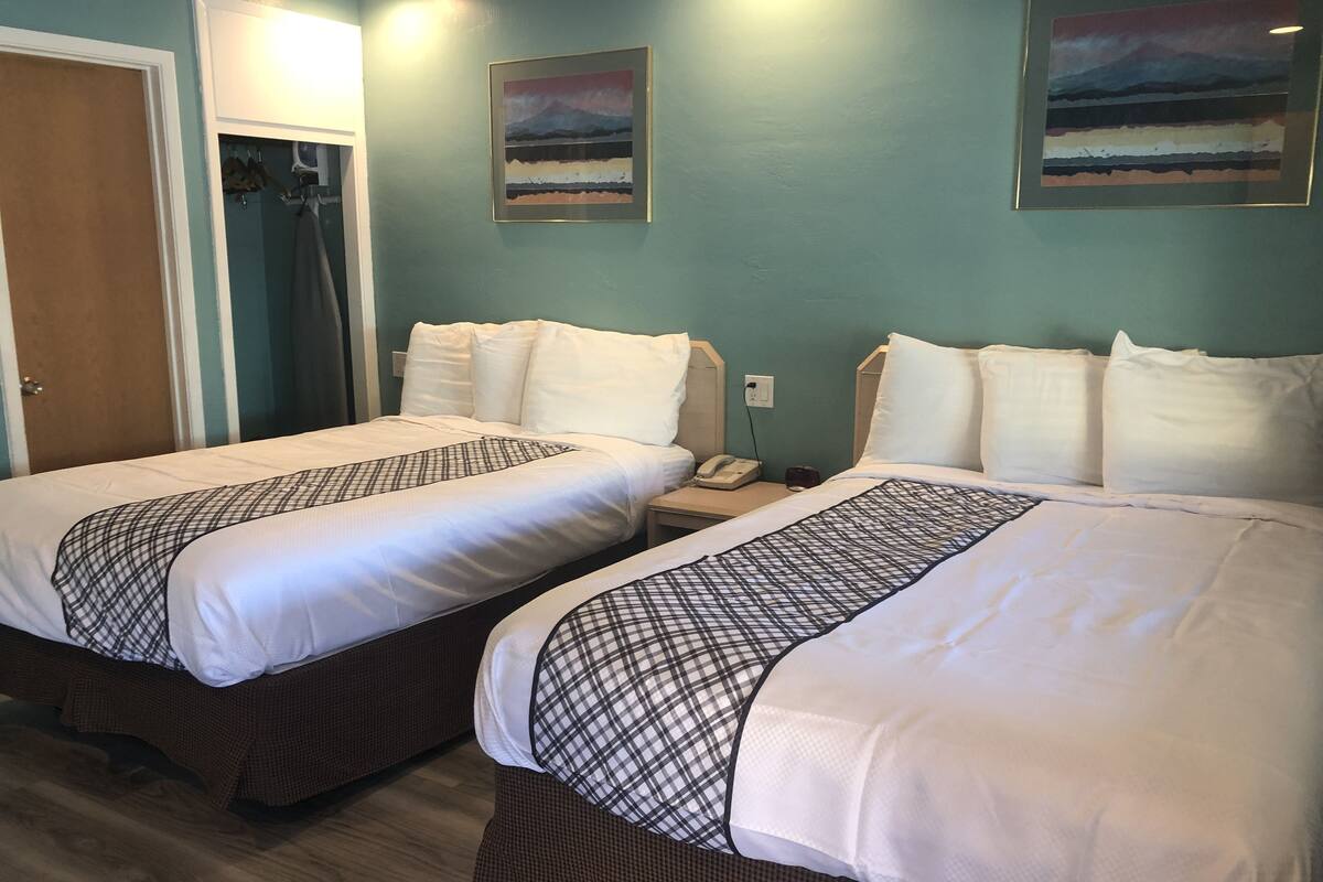 Habitación de hotel con dos camas, piso de madera y un cuadro en la pared.