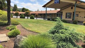A Bestway Inn with a covered outdoor seating area, neatly trimmed lawn, and various shrubs.
