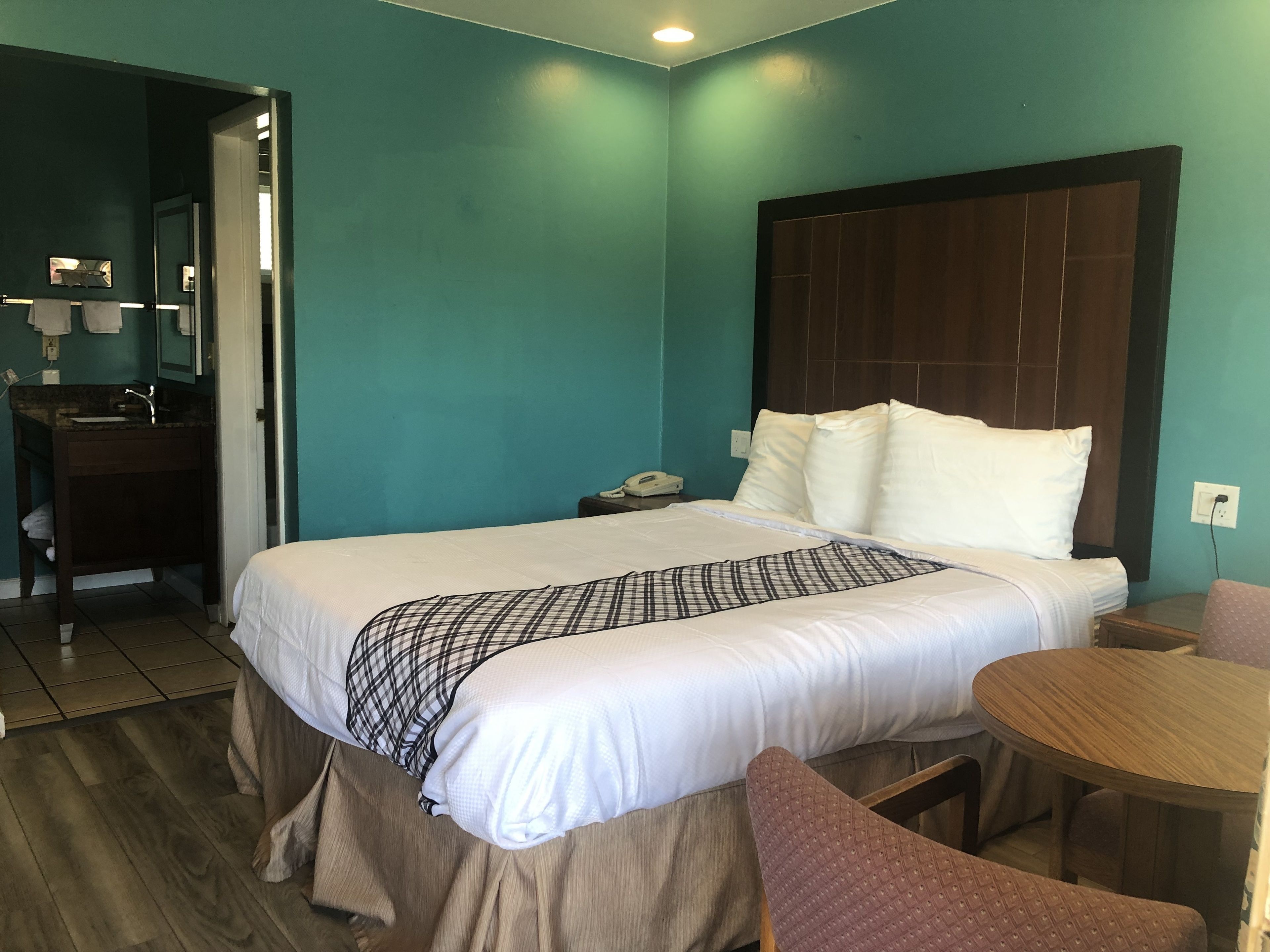 A hotel room with a bed, bedside table, and a small wooden table.