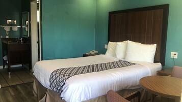 A hotel room with a bed, bedside table, and a small wooden table.