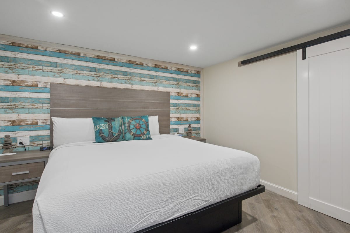 A bedroom with a bed, a nightstand, a dresser, and a wardrobe.