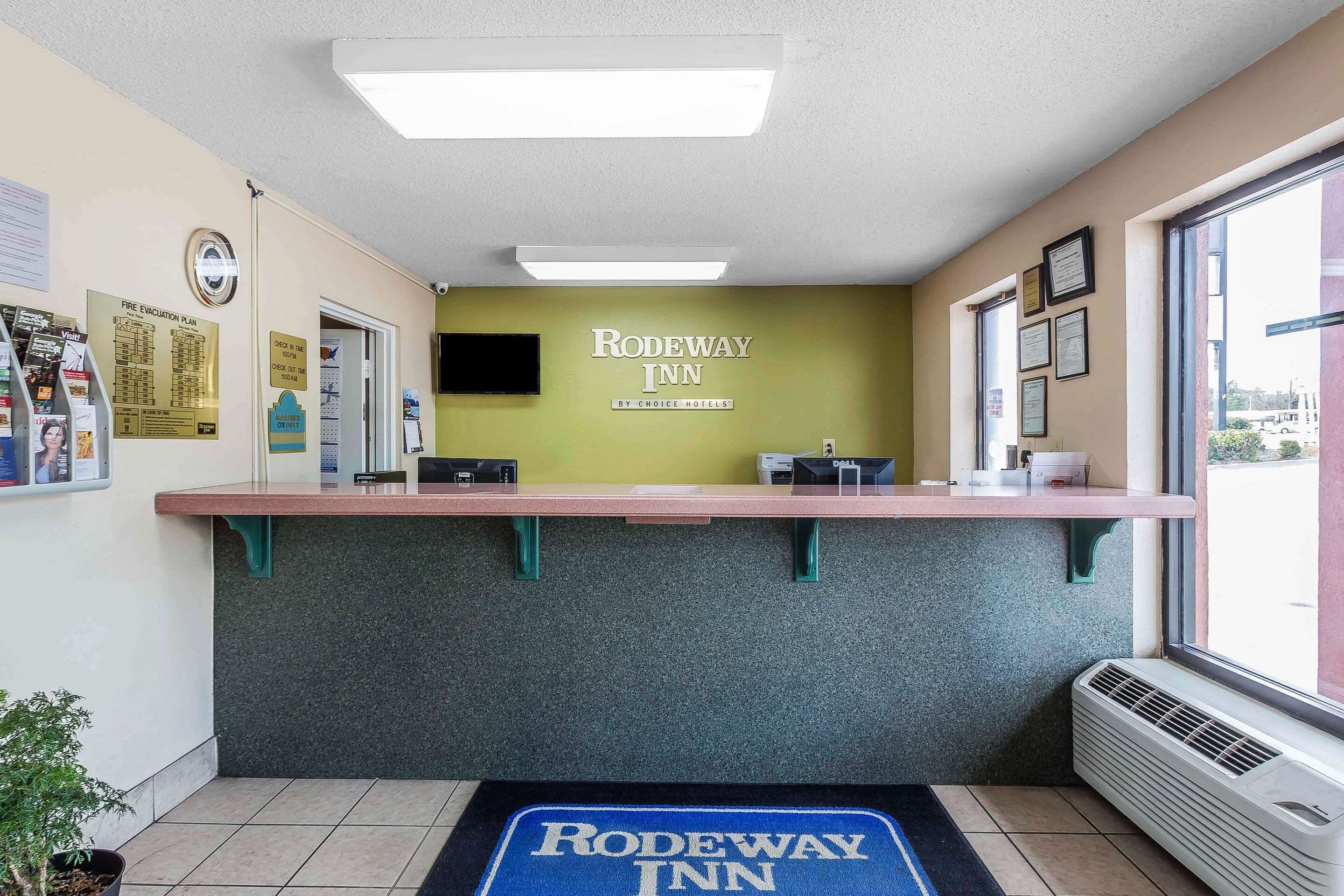 A reception area with a reception desk, a fire evacuation plan poster, and a sign for the Rodeway Inn.