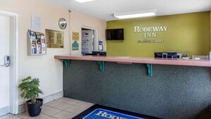 A reception area with a counter, a potted plant, and a sign for Rodeway Inn. - Rodeway Inn Augusta South (Augusta)