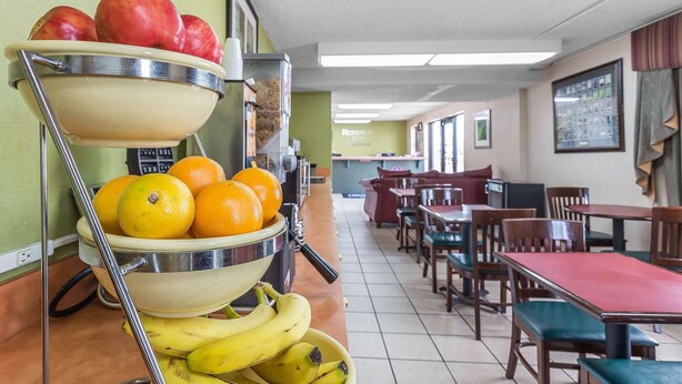 A cafeteria with fruit display, wooden tables, and chairs. - Rodeway Inn Augusta South (Augusta)