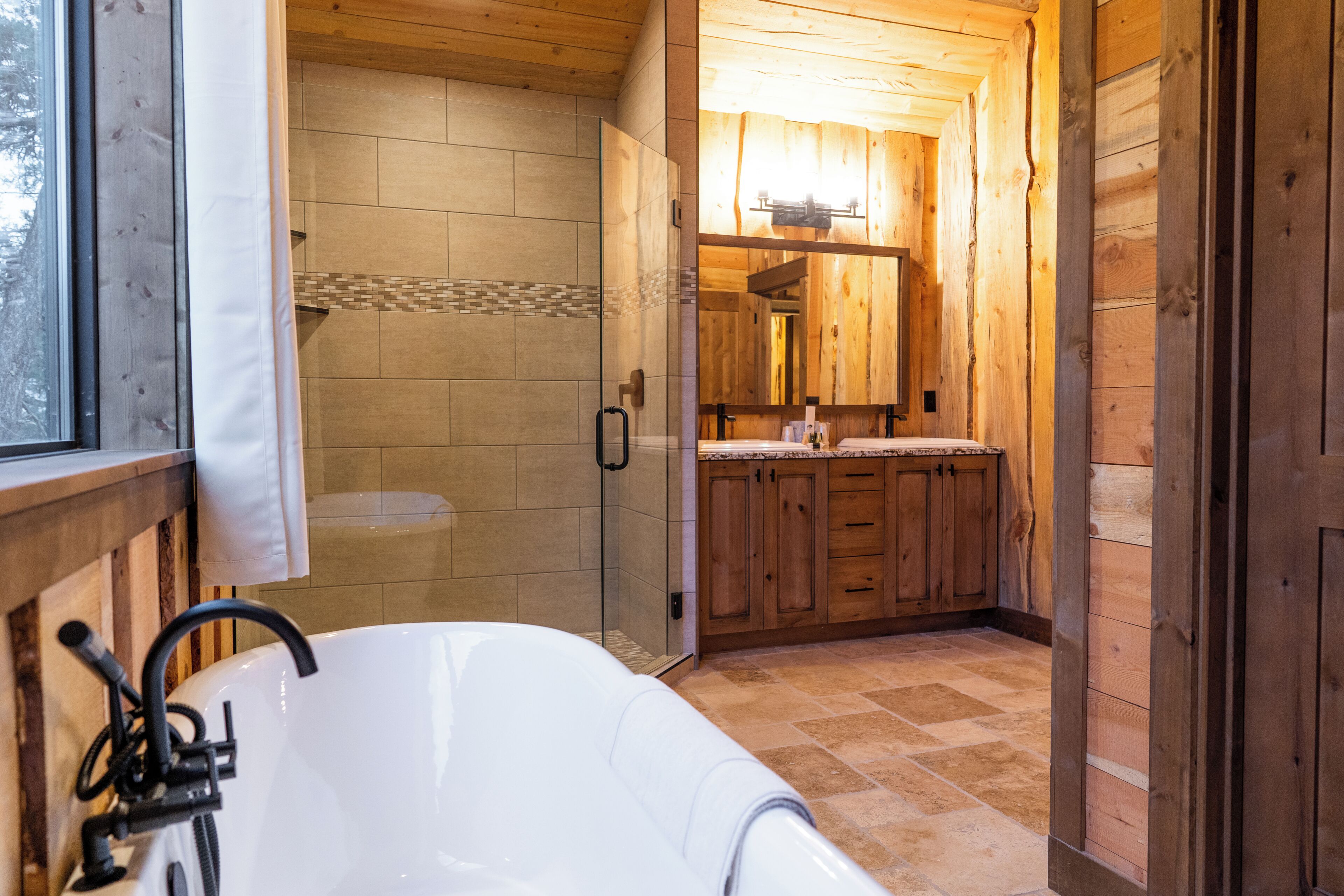 A bathroom with a bathtub, a shower, and a wooden vanity with a mirror.