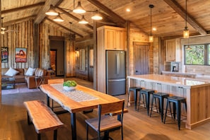 Un intérieur en bois avec un îlot de cuisine, des tabourets de bar et un réfrigérateur.