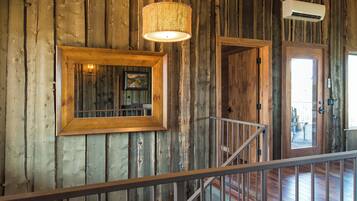 A wooden interior with a staircase, a hanging light fixture, and a framed picture on the wall.