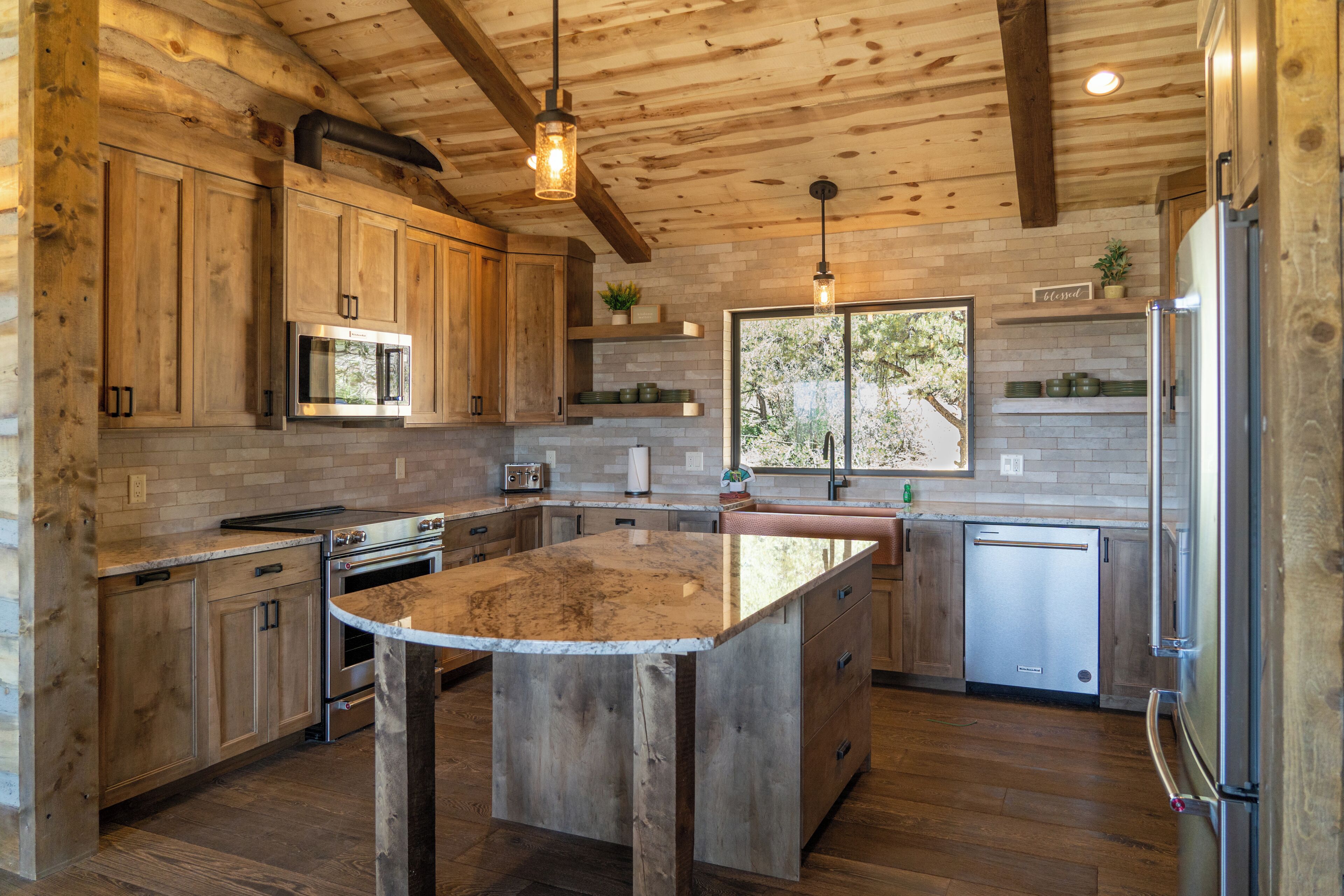 A kitchen with wooden cabinets, a central island, stainless steel appliances, and a large window.