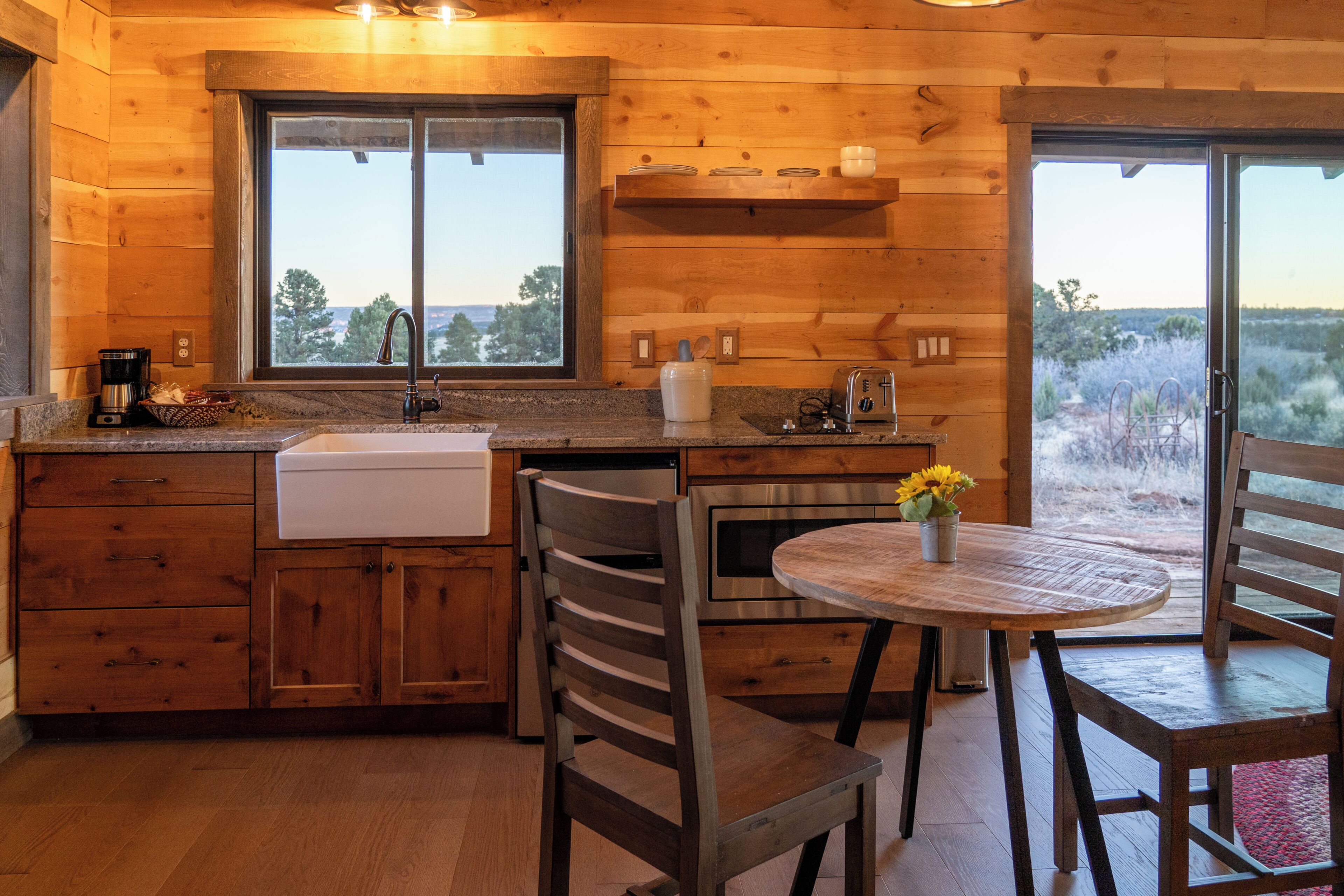 A wooden cabin kitchen with a sink, stove, and dining area.
