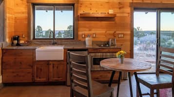 A wooden cabin kitchen with a sink, stove, and dining area.