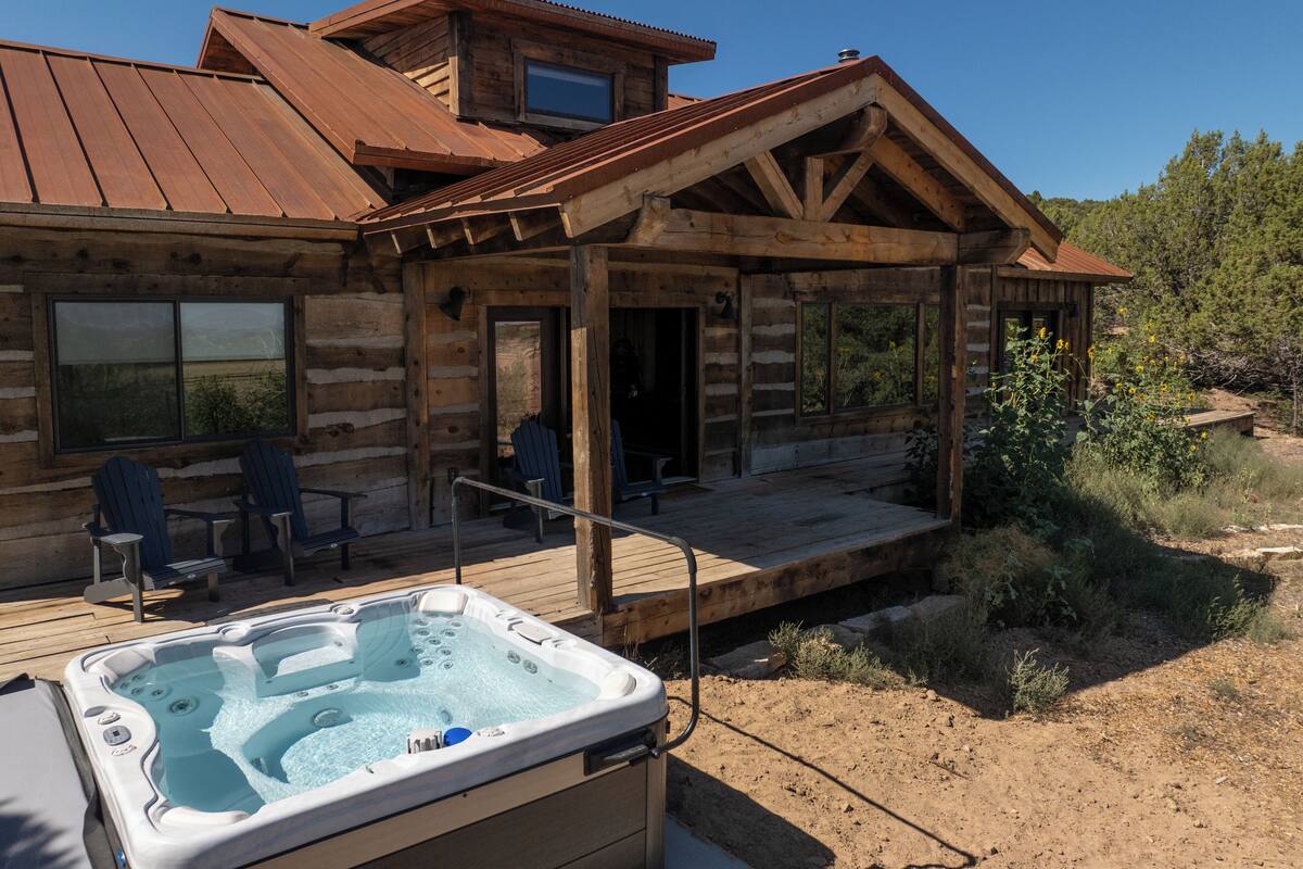 A log cabin with a hot tub, outdoor seating, and a deck.