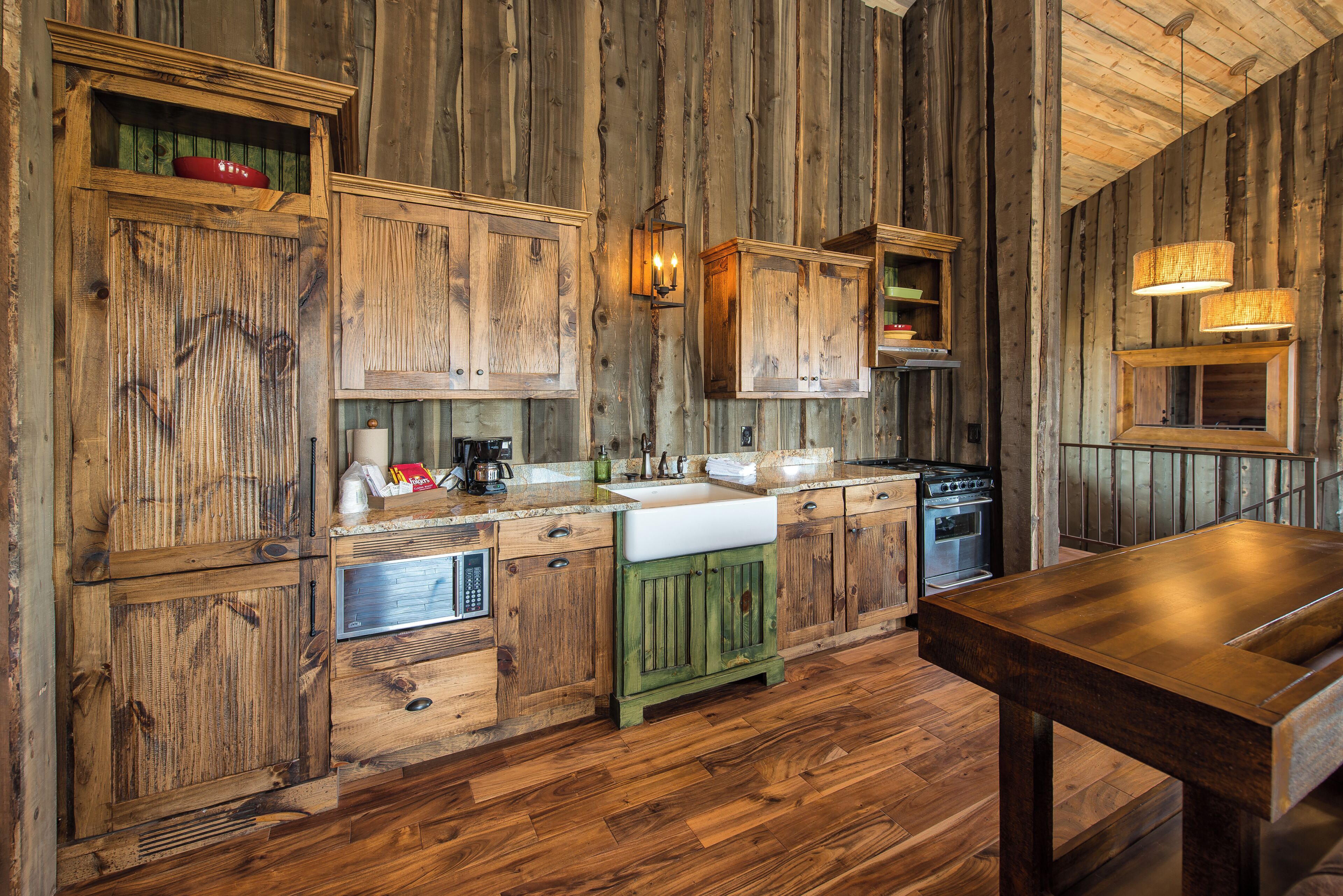 A rustic kitchen with wooden cabinetry, a sink, a stove, and a dining table.