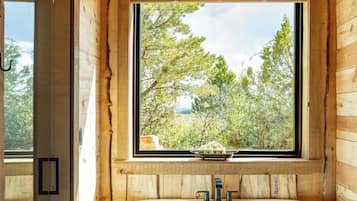 Une salle de bain moderne avec une baignoire sur pieds, une fenêtre donnant sur la forêt et des murs en bois.