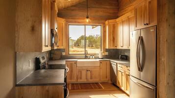 Una cocina con armarios de madera, un refrigerador de acero inoxidable y un ventanal con vistas al exterior.