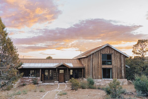 A rustic wooden building with a large front door, a covered porch, and a stone pathway leading to the entrance.