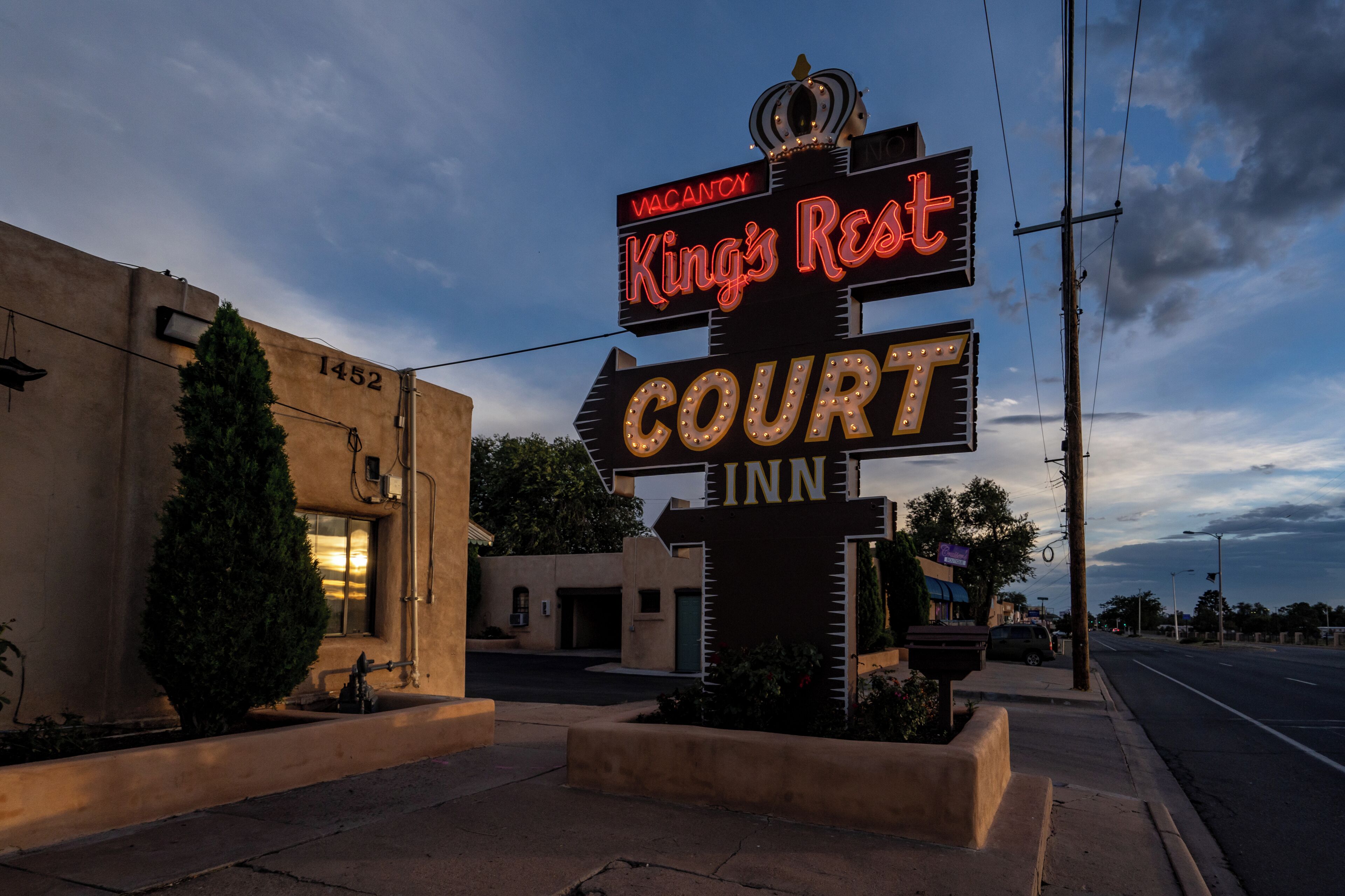 Een hotelschiltje met de tekst 'King's Rest Court INN' en een 'VACANCY' bordje.