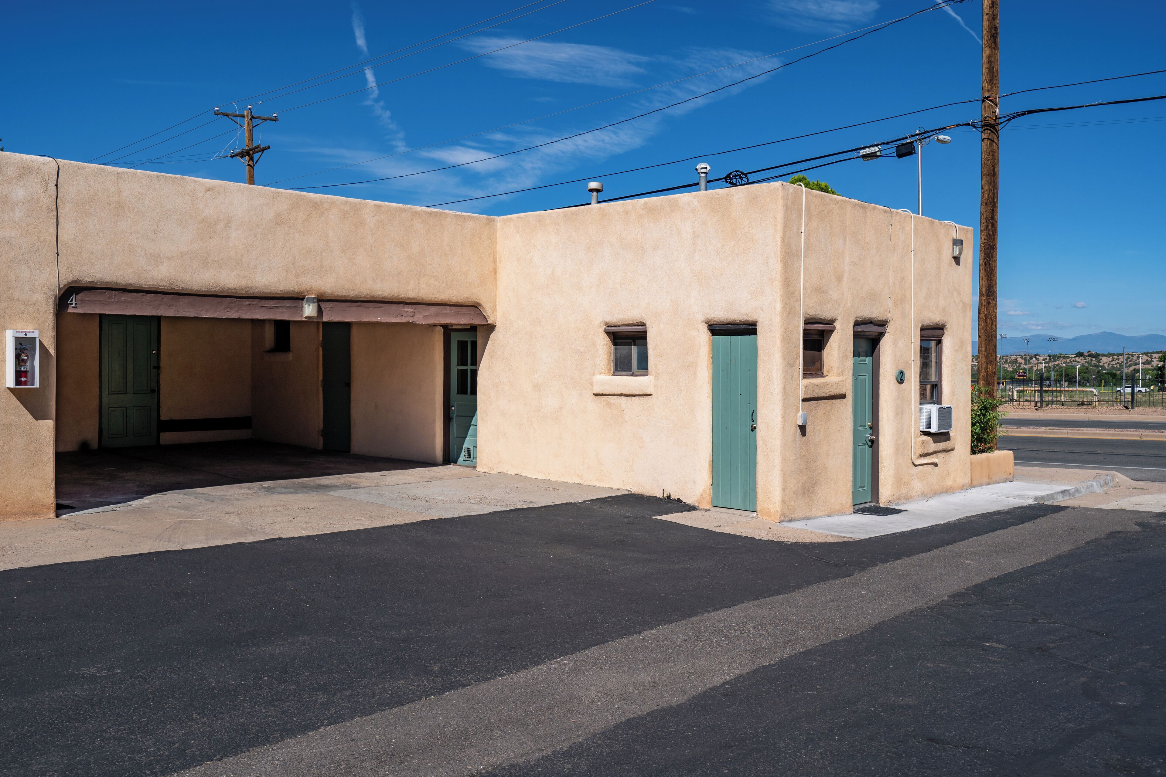 Un edificio con garaje, una puerta verde y un ventanal pequeño.