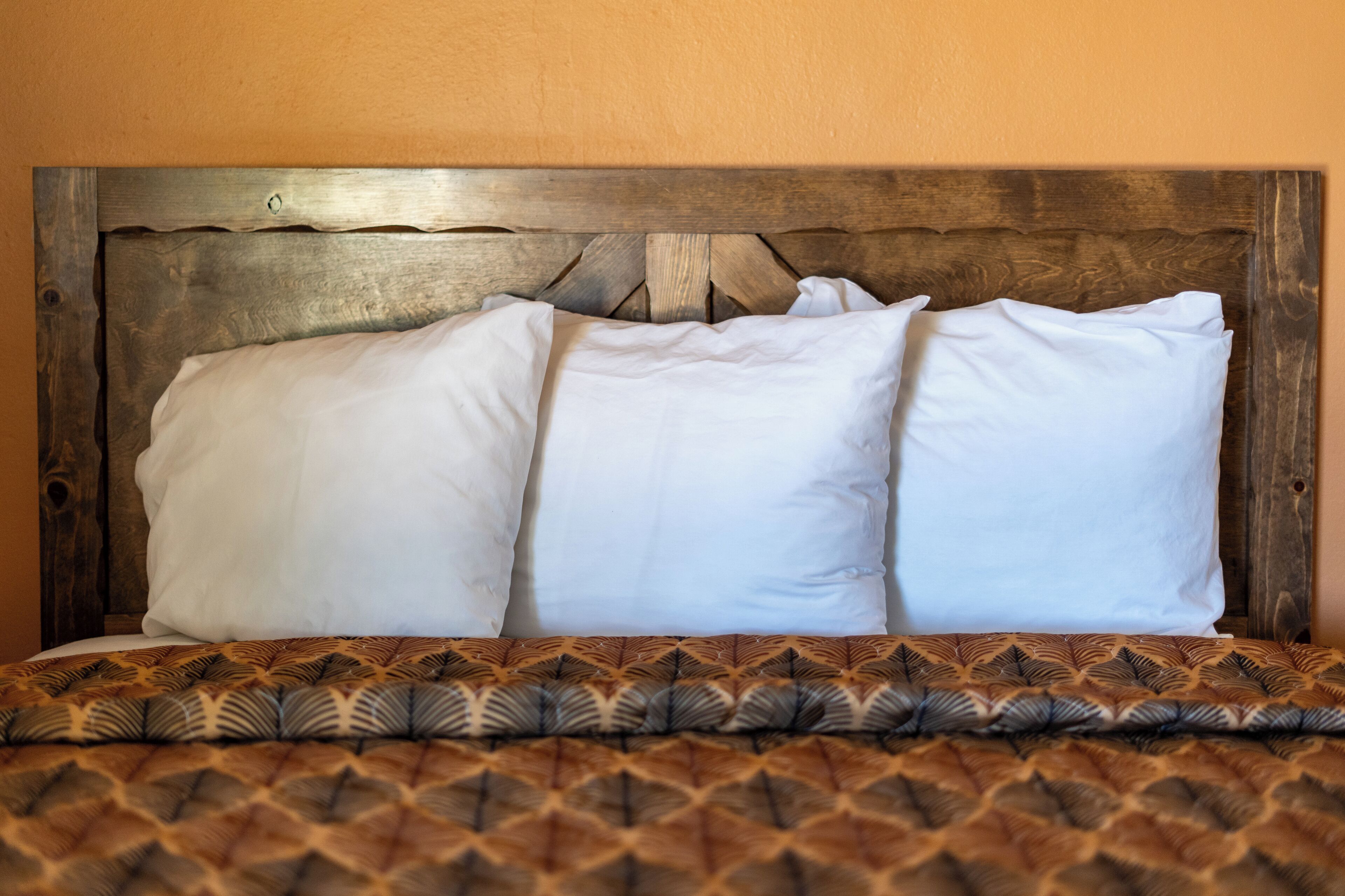 Una cama con cabecera de madera y colcha estampada.