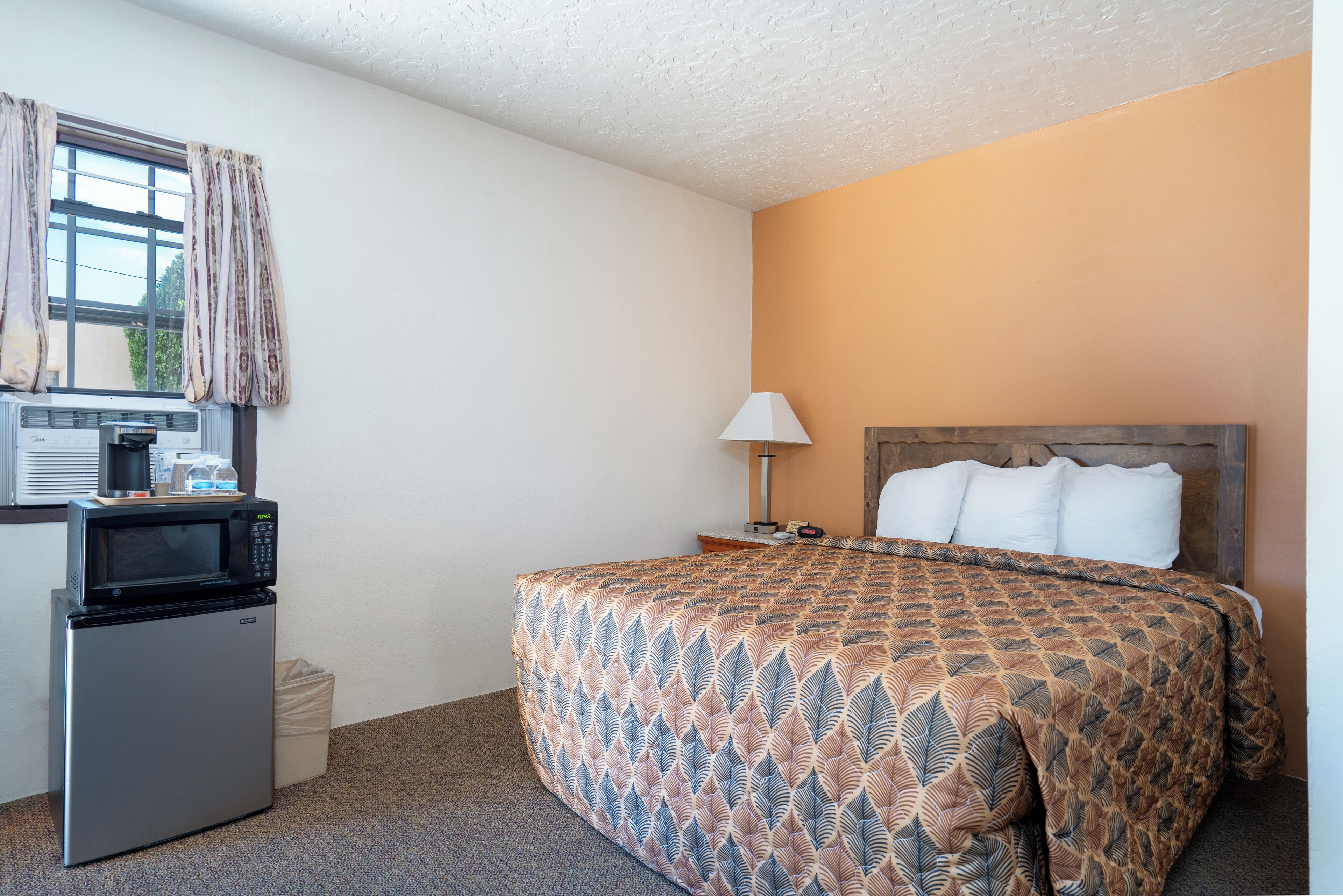 Ein Hotelzimmer mit einem Bett, einer Mikrowelle, einer Lampe und einem kleinen Kühlschrank.