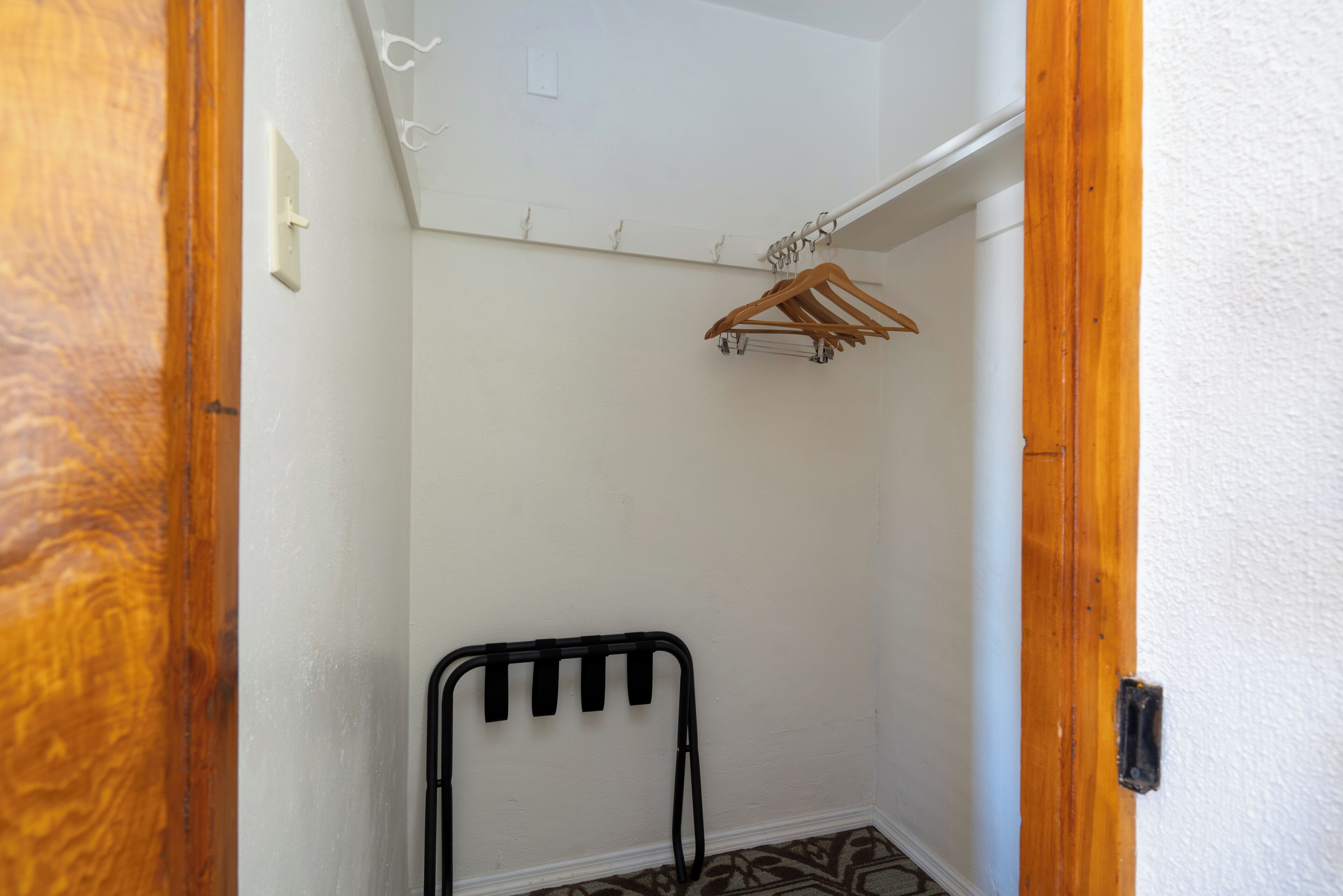 A small, narrow hallway with a wooden door frame, a black metal radiator, and a wooden coat rack.