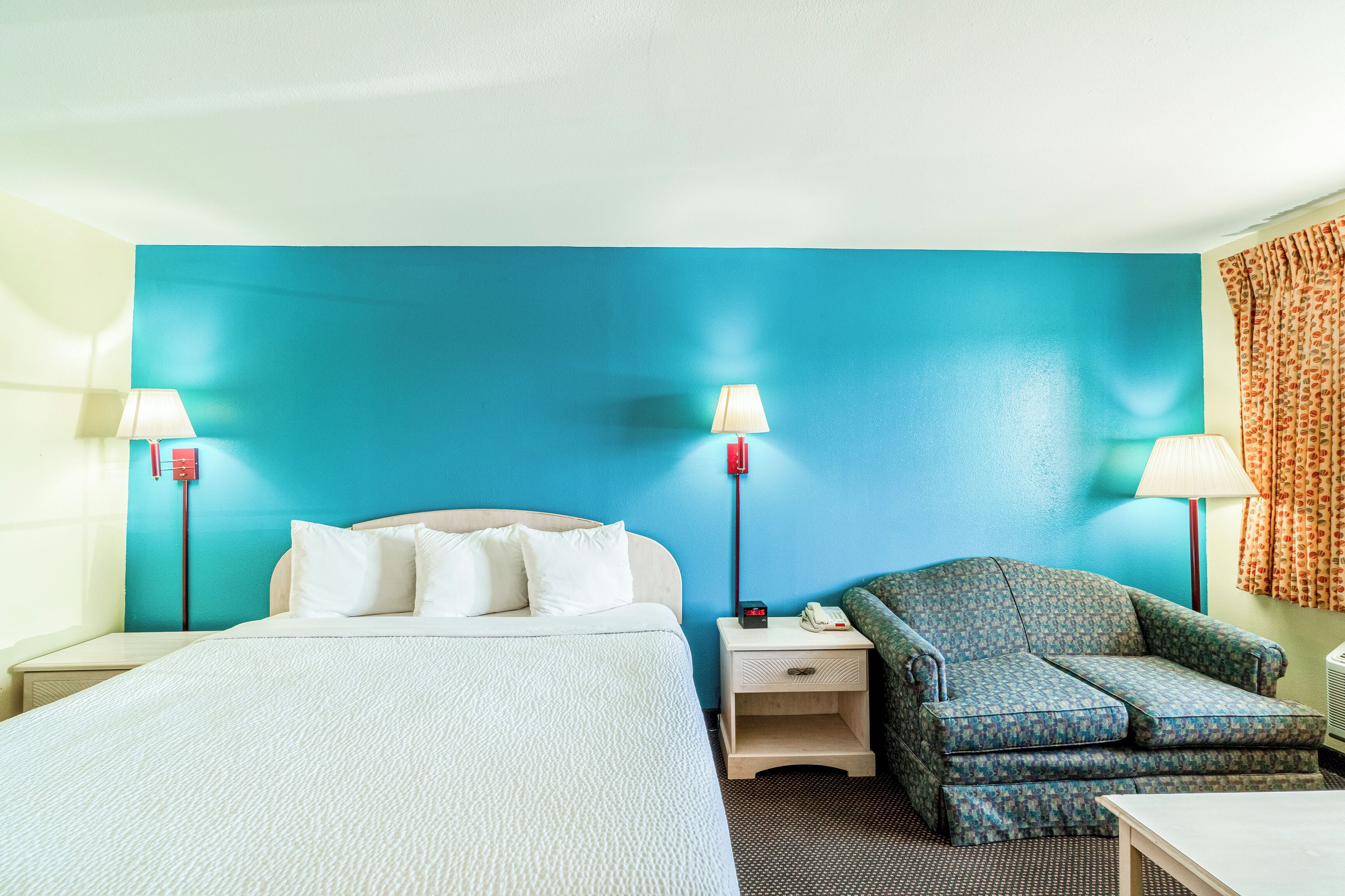 A hotel room with a bed, two bedside tables with lamps, a chair, and a small table.