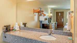 A hotel bathroom with a granite countertop, sink, and mirror. - Shale Inn Andrews (Andrews)
